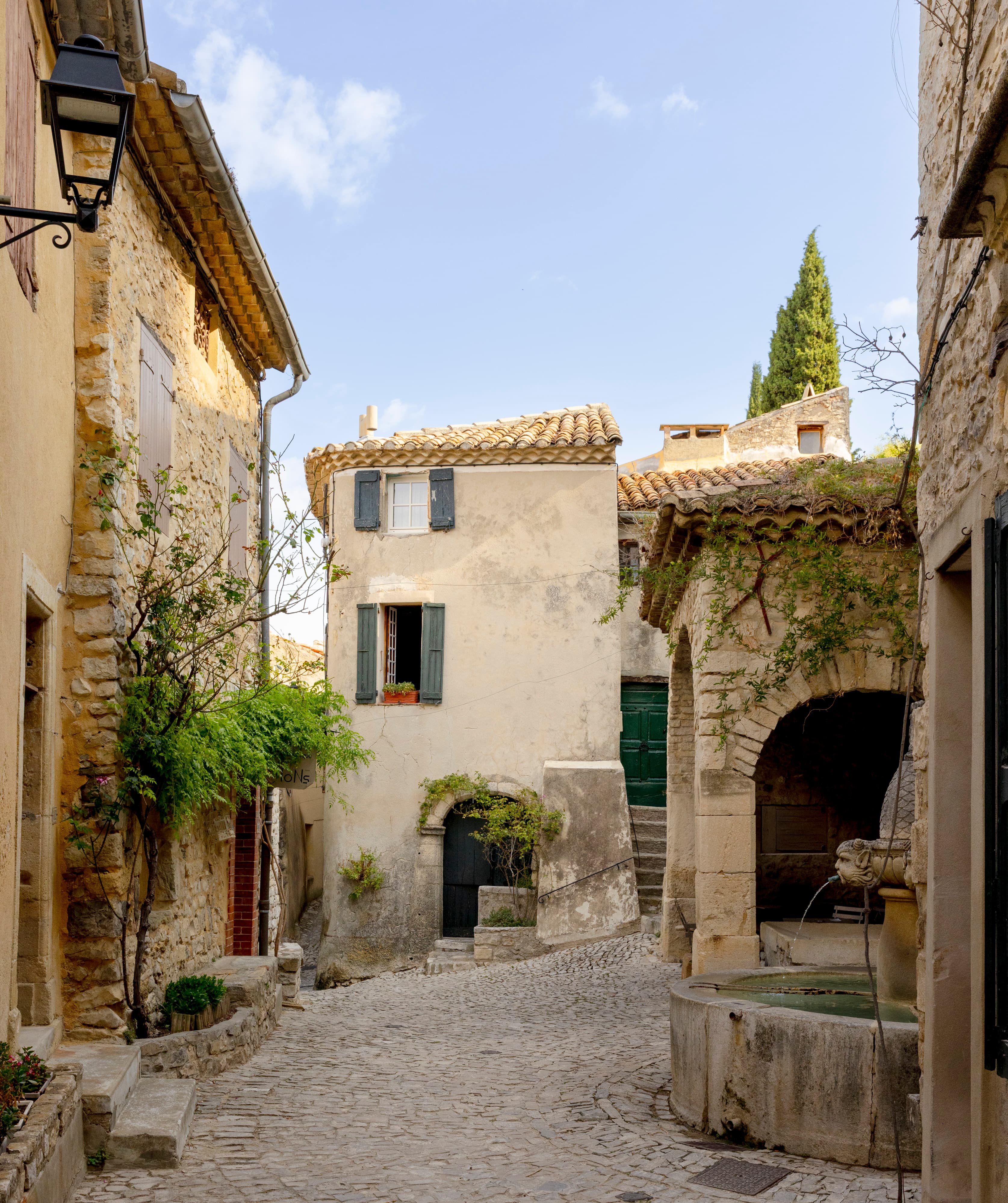 Eine gepflasterte Gasse und der Brunnen des Dorfes Séguret